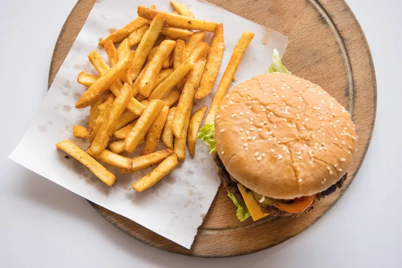 A cheeseburger with chips on a wooden board