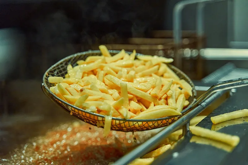 Chips lifted out of a fryer in a wire basket