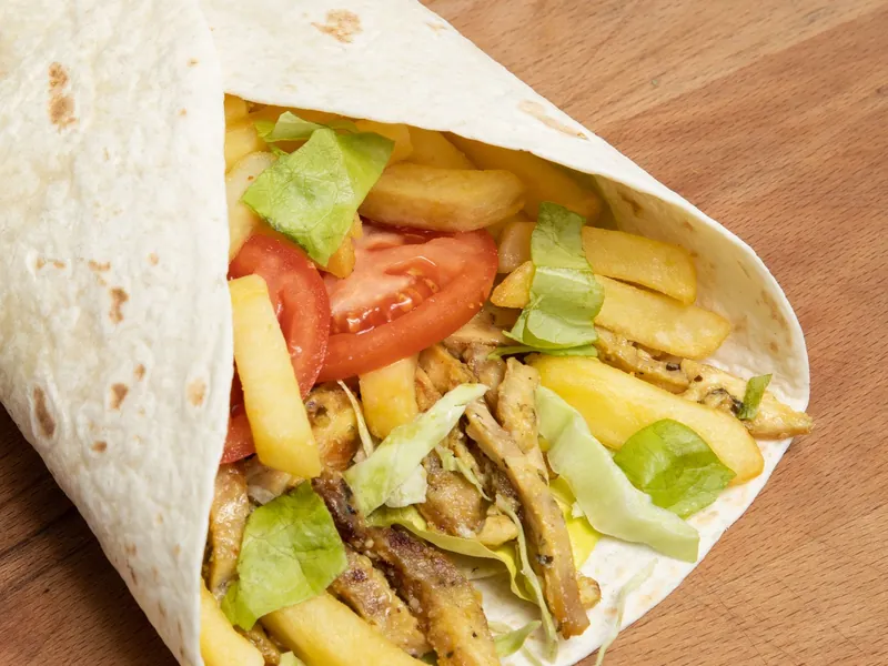 A wrap filled with chips, chicken and salad